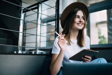 Modayı takip eden yaratıcı kadın serbest yazar, kafeteryada oturup proje üzerinde çalışırken iş fikirlerini düşünür ve başka yöne bakar.