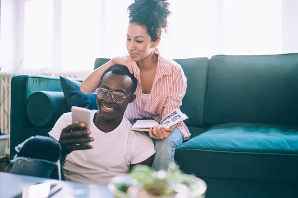 Divers Jeunes Souriants Couple Joyeux Utilisant Téléphone Pendant Repos Maison — Photo