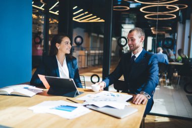 İki iş arkadaşı iş hakkında zevkle konuşuyor. Toplantı odasında masada otururken tablet kullanıyorlar.