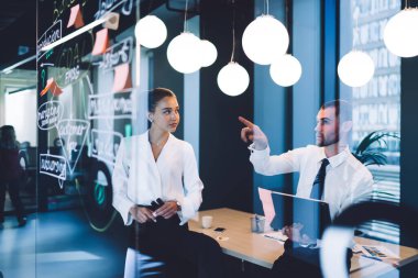 Cam duvara dizüstü bilgisayarı olan resmi işadamının yansıması ve şirket stratejisini bayan meslektaşlarına açıklamak.