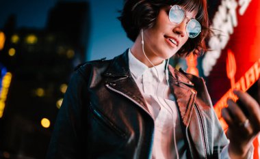 Klasik gözlüklü milenyum blogcusu, çevrimiçi mesajlaşma için cep telefonunu kullanarak elektronik kulaklıklarda güzel bir etki yaratan, müzik podcast 'i kurmak ve dinlemek için medya uygulamasını arıyor