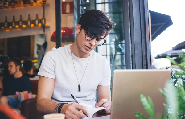 Sério Homem Pensativo Óculos Escrevendo Notas Bloco Notas Navegando Internet — Fotografia de Stock