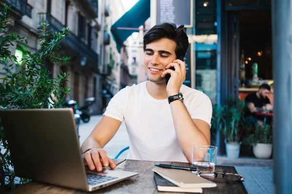 Homem Positivo Usando Laptop Falando Smartphone Enquanto Sentado Café Com — Fotografia de Stock