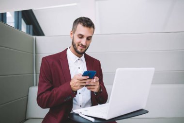 Zarif takım elbiseli pozitif etnik serbest yazar ofis masasında otururken uzaktan kumandalı iş sırasında arkadaşıyla sohbet ediyor.