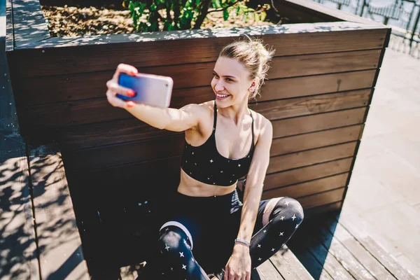 Pleased Blond Haired Female Sportswear Resting Crossed Lags While Smiling — Stock Photo, Image