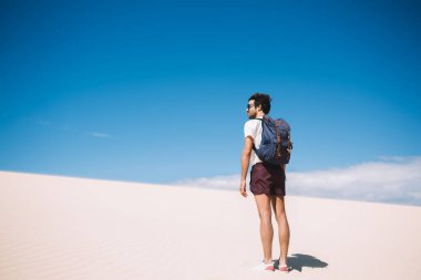 Beyaz Kumlar Ulusal Parkı 'na giderken ısıtmalı güneş ışınları altında duran erkek gezgin, kurak toprakların üzerinde nefes kesen çöl ve gökyüzü manzarası ile açık havada dolaşır.
