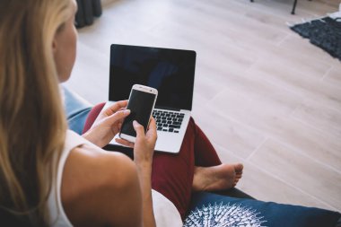 Bin yıllık serbest çalışan kadın resminin kırpılmış görüntüsü, uzaktan kumandalı akıllı telefon aygıtı ile ilgili web bilgilerini kontrol ederken, kopyalama alanı olan modern teknoloji üzerine seçici odaklanma