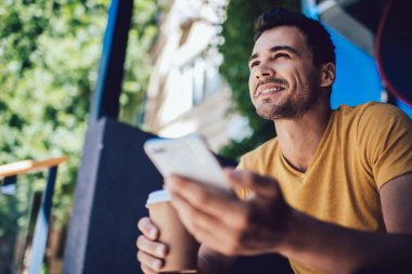 Neşeli Kafkasyalı Kafkasyalı hippi, açık havada akıllı telefon tutarak ve mesajlar göndererek vakit geçiriyor. Milenyum erkek blogcusu sosyal ağlarda medyayı paylaşmaktan keyif alıyor.