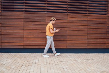 Stil odaklı barışçıl bir adamın yaz aylarında şehir duvarında gezerken cep telefonuyla gezdiği görüntüler.