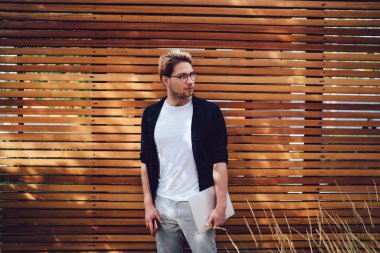 Sıradan kıyafetler ve gözlüklü, dizüstü bilgisayarı ve cep telefonu olan sakin bir genç adam sokaklarda gözlerini kaçırarak vakit geçiriyor.