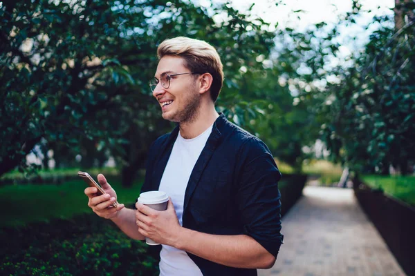 Счастливый Молодой Человек Повседневной Одежде Несет Напиток Пойти Просматривать Смартфон — стоковое фото