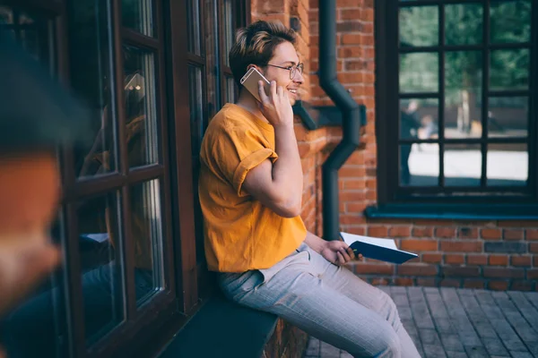 Vrolijke Man Bril Causale Kleding Zittend Baksteen Muur Vensterbank Spreken — Stockfoto