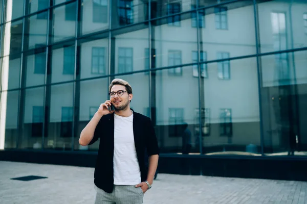Optimistisk Ung Man Med Handen Fickan Ler Och Talar Smartphone — Stockfoto