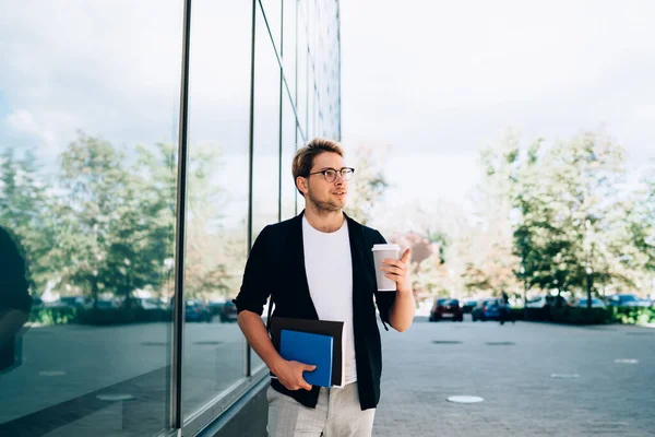 Young Man Notebooks Takeaway Beverage Pointing Aside Looking Away While — Stock Photo, Image