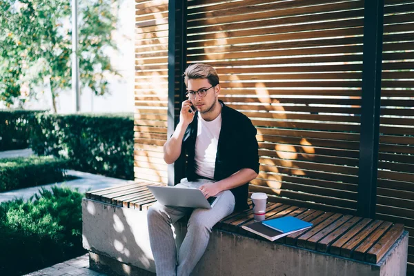 Freelancer Jovem Focado Usando Laptop Ter Conversa Smartphone Enquanto Sentado — Fotografia de Stock