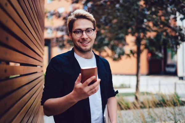 Gioioso Giovane Maschio Abbigliamento Casual Occhiali Utilizzando Messaggistica Cellulare Con — Foto Stock