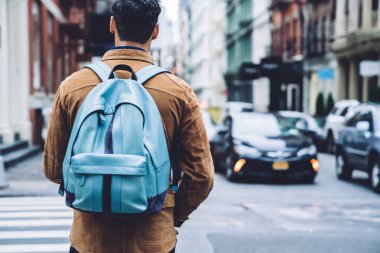 Koyu renk saçlı, kahverengi süet ceketli, mavi deri ceketli, New York 'ta yaya geçidinde el ele duran son moda erkek turistin arka görüntüsü.