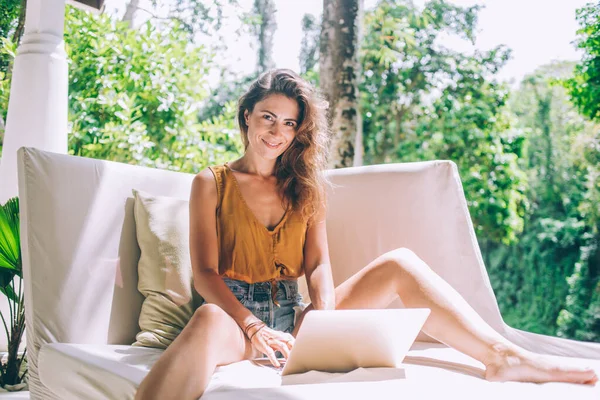 Прекрасний Усміхнений Сучасний Контент Випадкової Молодої Жінки Переглядає Ноутбук Сидячи — стокове фото