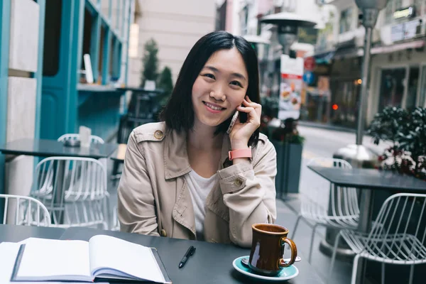 Vrolijke Etnische Casual Vrouw Beige Regenjas Zitten Aan Tafel Met — Stockfoto