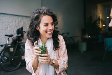 Modayı takip eden neşeli esmer kadın kafede oturup boş zamanlarında soğuk yaz kokteyli içiyor, eğlenceli 20 'li yaşlarda, boş zamanların keyfini çıkarıyor ve elinde taze bir içecekle yemek molası veriyor.