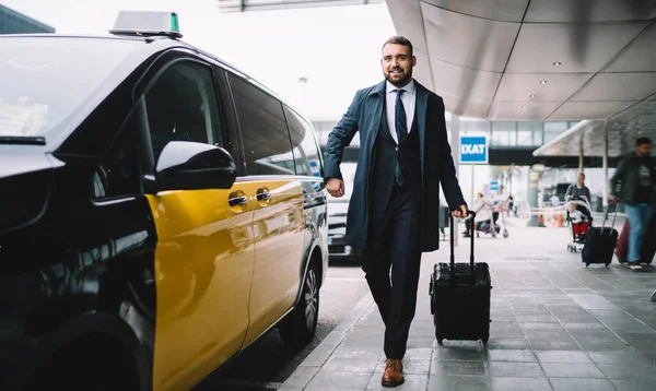 空港ターミナルの近くの通りにタクシーに歩いている間 正式な着用手荷物を保持し 楽しみにして成功したビジネスマンを確信してください — ストック写真