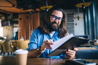 40 yıldır gülümseyen beyaz sakallı adam, planlamacıdan bilgi okuyor. Küçük işletme sahibi, vizyon düzeltme yazıları için zengin bir erkek girişimci.