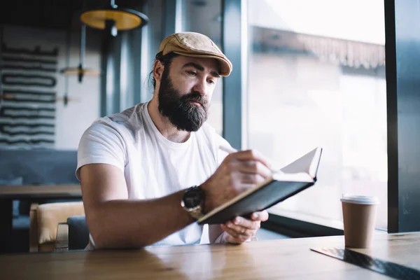 Serious Bearded Mature Man Hat Sitting Cafe Interior Writing Notepad — Stock Photo, Image