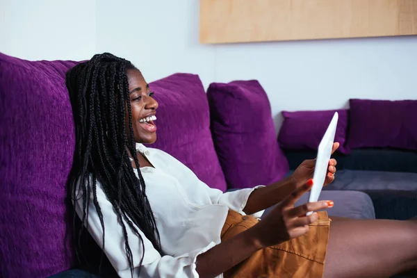 Cheerful african american woman laughing at funny movie on digital tablet relaxing on free time at home, emotional overjoyed dark skinned female amazed with sals in web store browse on touchpad