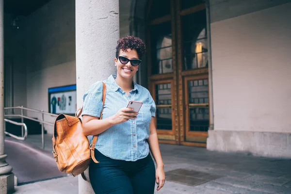 携帯電話のガジェットを保持バックパックを持つおもちゃの女性旅行観光客の半分の長さの肖像オンラインネットワーキングを作るための カメラで笑顔モバイルデバイスを持つ幸せな繁栄留学生 — ストック写真