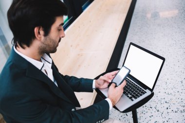 Yukarıdaki resmi işadamından, çağdaş iş yerinde yedek kulübesinde otururken bilgisayarla akıllı telefondan mesajlaşma mesajı.