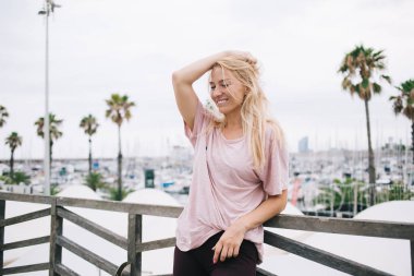 Şehirde günlük kıyafetlerle gezen mutlu sarışın gezgin ve dünyayı keşfetmek için tek başına tatil yaparken gülümseyen kaygısız beyaz kız turistik şehirde boş zamanlarında kendini iyi hissediyor.