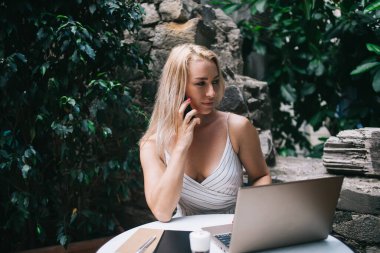 Yazılım projesi detayları hakkında uluslararası cep telefonu konuşması yapan yetenekli kadın, müşteri hizmetleriyle konuşmak için gezgin internet bağlantısı kullanan beyaz kadın.