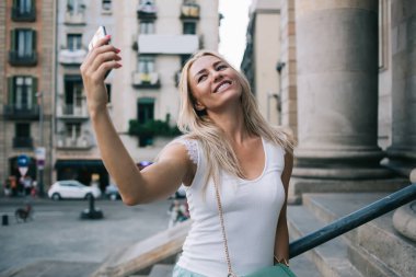 Neşeli Kafkasyalı kadın geziler hakkında video blogu çekmek için ön telefon kamerasını kullanıyor, mutlu milenyum turistleri mobil cihazlarda filtre uygulaması kullanarak selfie çekiyorlar.