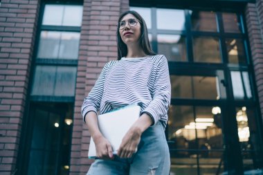 Şehir merkezinde dikilip düşünceli bakışlı, optik klasik gözlüklü Latin öğrencilerin şehir caddesinde düşündüğü, vizyon koruması için şık gözlüklü yetenekli serbest çalışan biri.