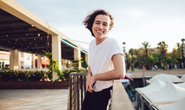 Moda modası geçmiş genç adam Barcelona 'da balkonun ahşap çitlerine yaslanırken gülüp kameraya baktığı için mutlu.