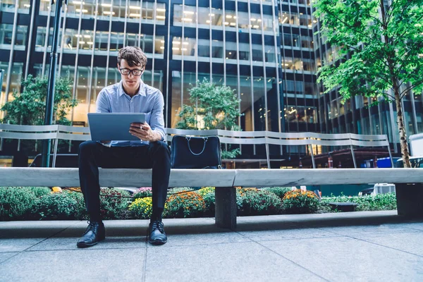 Schöner Fokussierter Junger Mann Mit Brille Sitzt Auf Einer Bank — Stockfoto