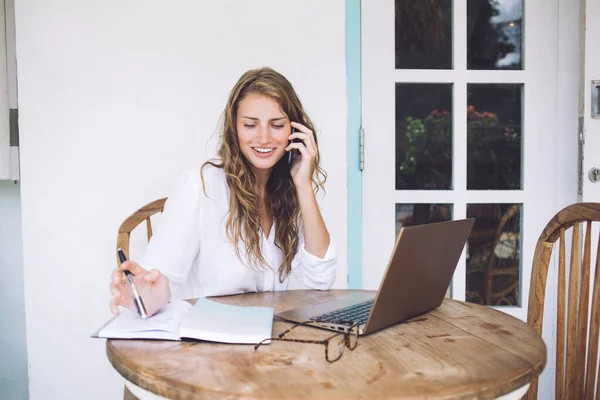 Mulher Atraente Alegre Branco Usando Notebook Falando Telefone Enquanto Sentado — Fotografia de Stock