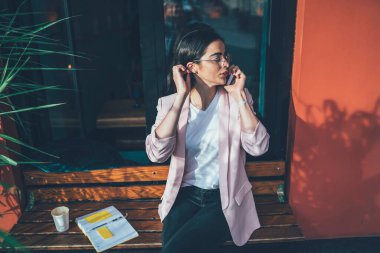 Gürcü kadın şık günlük kıyafetler giyip uluslararası akıllı telefon konuşmaları yaparak kaldırımda organizasyon kuruyor, gözlüklü güzel kız öğrenci mobil uygulama üzerinden arıyor.