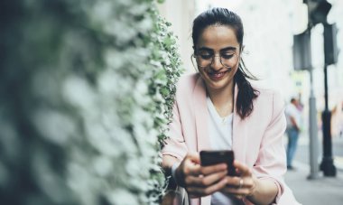 Göz düzeltmesi için optik gözlüklü neşeli kadın milenyumu modern akıllı telefon teknolojisinde yüksek hızlı internet bağlantısı kullanan sosyal takipçilerle mobil sohbet sırasında gülümsüyor, Y jenerasyonu.