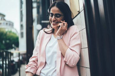 Gözlüklü neşeli hippi kız uluslararası iletişim numarasını çevirdiği için 4G 'ye bağlanıyor ve hareketlilik uygulaması aracılığıyla arkadaşça sohbet ediyor, konuşurken başarılı bir kullanıcı gülüyor.