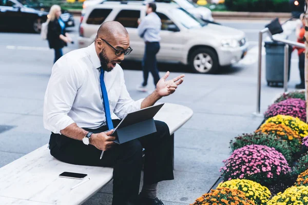 位于市中心的平板电脑屏幕上的交易结果让身着正式服装 戴着眼镜的非洲裔美国成年男性吃惊不已 — 图库照片