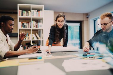 Modern çalışma alanındaki işbirliği sırasında başlangıç tasarımı projesi geliştiren ilerici çok ırklı erkek ve kadın mimarlar, masaüstünde gelişigüzel beyin fırtınası yapan akıllı bir grup.