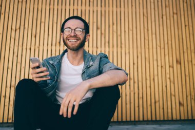 Cep telefonu cihazını elinde tutan ve şehir ortamında boş zamanlarında kameraya gülümseyen, cep telefonu teknolojisi tutan neşeli blogcu binlerce yıl boyunca etkili bir ressam portresi.