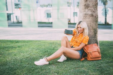 Genç hippi kız, Vlog yayınlarını etkilemek için ön cep telefonu kamerasını kullanıyor, beyaz kadın yalnız tatillerde eğleniyor, takipçilerle internet iletişimi kurmak için akıllı telefon blogundan keyif alıyor.