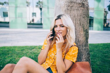 Modern teknoloji ile hücresel iletişim kuran çekici hipster kız portresi, cep telefonuyla dolaşırken kameraya bakan çekici kadın milenyumu.