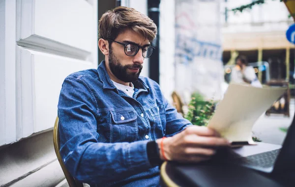 Thoughtful Male Freelancer Denim Jacket Eyewear Taking Paper While Sitting — Stock Photo, Image