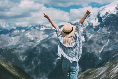 Lago di Braies yakınlarında bulutlu bir günde dağ sırtında dikilirken kollarını sıkan ve esneyen sıska bir kadının arka görüntüsü.