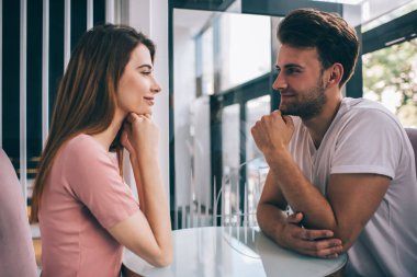 Gülümseyen mutlu çiftin yan görünüşü. Kafenin karşısında otururken birbirlerine şefkatle ve özenle bakıyorlar.