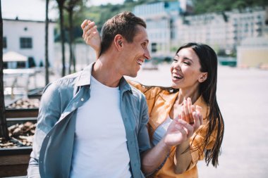 Neşeli, gülen bir çift, güneşli bir günde modern şehir caddesinde gezintiye çıkıyorlar. Birbirlerine sevgiyle bakıyorlar.