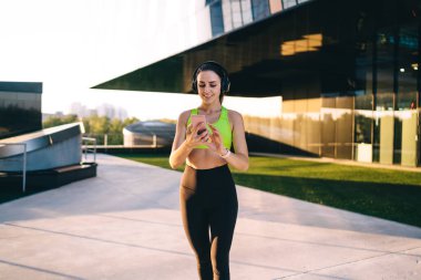  Aktif olarak çalışan genç, zayıf bir kadın stadyumda spor yapıyor, vücudunun alt kısımları için egzersiz yapıyor, Kafkasyalı bir kız forma hedeflerini koruyor, enerji için çalışıyor, kulaklıkla müzik dinliyor.